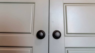 Panorama yatak odasının içi parlak çift ahşap kapılı ve mat siyah yuvarlak düğmeli.