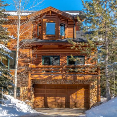 Park City 'de ahşap bir evin ön cephesinde kare mahsullü garaj kapısı balkonu ve defne penceresi.