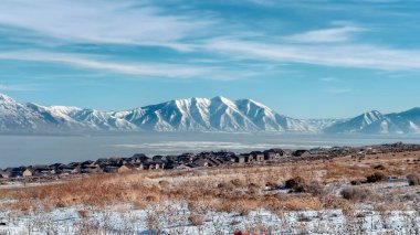 Panorama Rugged Wasatch Dağları ve buzlu Utah Gölü. Önünde karlı bir arazi var.