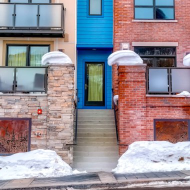 Kare çerçeve. Renkli duvarlı apartman cephesi ve cam parmaklıklı balkonlar.