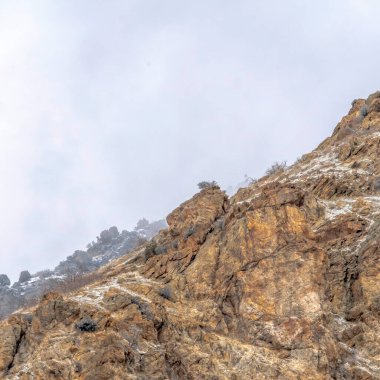 Utah 'taki kayalık Prvo Kanyonu' nun karlı zemini bulutlu gökyüzü arkaplanına sahip.