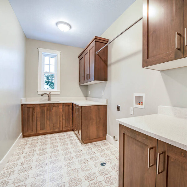 Square Kitchen interior with brown wooen cabinets white countertops sink and window