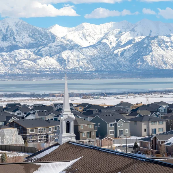 Plaza Iglesia aguja contra casas de barrio con montaña nevada y vistas panorámicas al lago —  Fotos de Stock