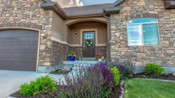 Panorama crop Facade of home with lush yard in front of stone wall and gable roofs — Stock Photo, Image