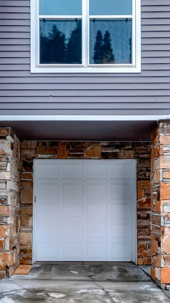 Cosecha vertical Puerta de garaje con paneles blancos de la casa con revestimiento gris y pared exterior de piedra — Foto de Stock