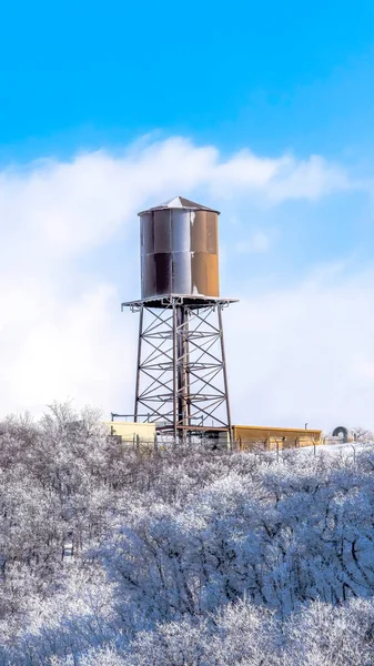 Vertical crop Water tank storage container on a tower at the snowy slope of Wasatch Mountains