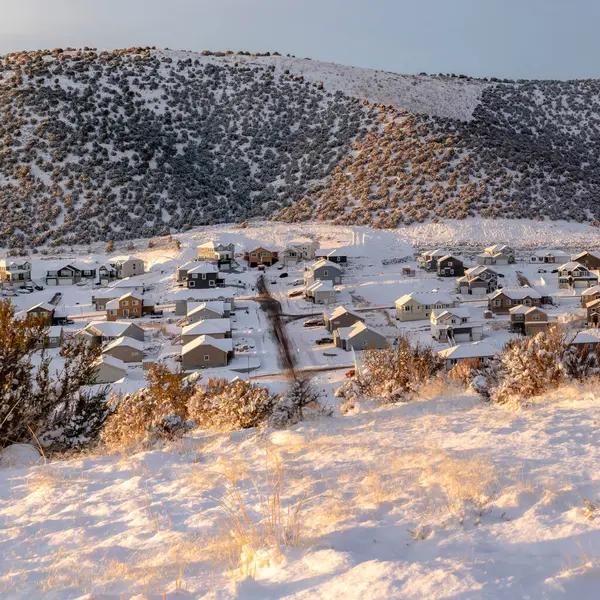 Casas cuadradas en medio de colinas cubiertas de nieve fresca de invierno bajo el cielo azul nublado — Foto de Stock