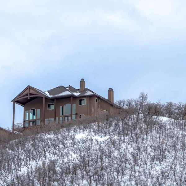 Case quadrate sulla cima di una collina con cespugli senza foglie marroni sul pendio innevato in inverno — Foto Stock