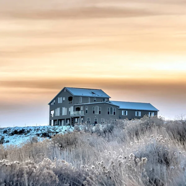 Square frame Home sitting on snowy hill with golden cloudy χειμωνιάτικο φόντο στο ηλιοβασίλεμα — Φωτογραφία Αρχείου