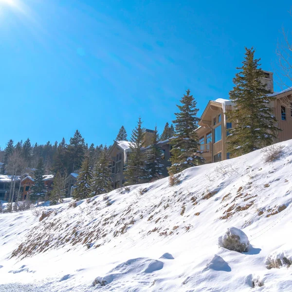 Cultivo cuadrado Fachada de hermosas casas en una pendiente cubierta de nieve blanca en un día soleado de invierno — Foto de Stock