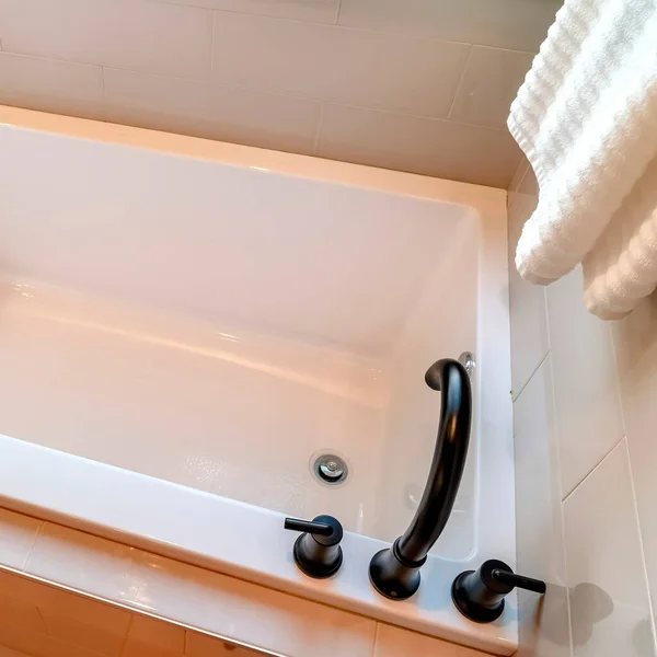 Bañera rectangular cuadrada con grifo negro y asas contra pared y suelo de baldosas — Foto de Stock