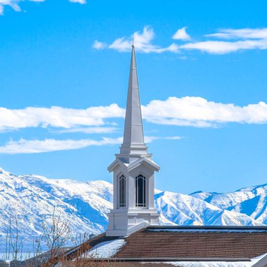Kilisenin kare çerçeveli çatısı karlı dağ ve göle karşı modern bir kule tasarımı var.