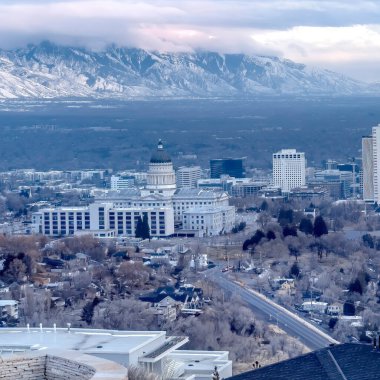 Salt Lake City şehir merkezine bakan kare kare tepe ve karla kaplanmış uzak dağ
