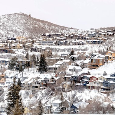 Kışın karlı bir mahallede evleri olan Utah Şehri 'nin kare çerçeveli dağları.