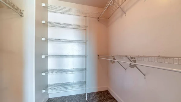 Marco panorámico Walk in closet con bastidores metálicos y varillas colgantes montadas en pared blanca lisa — Foto de Stock