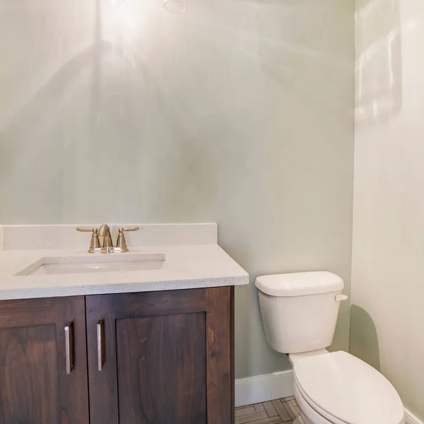 Kwadratowe zlewozmywak i kran na białym blatze nad drewnianą szafką obok toalety łazienkowej — Zdjęcie stockowe
