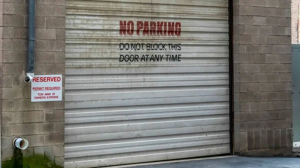 Panorama Corrugated metal garage door of an old brick building with No Parking sign — Stock Photo, Image