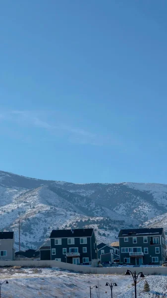 Vertical frame Row of houses against snow dusted hills and blue sky on a gloomy winter day