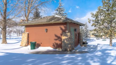 Panorama Deposu kalça çatılı ve kar ve bulutlu gökyüzüne karşı kahverengi ahşap duvarlı