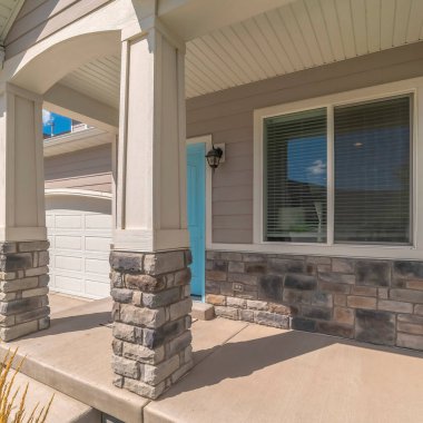 Evin verandasındaki kare kemerli giriş, pencerenin yanındaki mavi ön kapı.