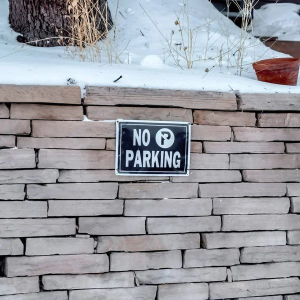 Marco cuadrado No hay señal de aparcamiento en un muro de contención de ladrillo de piedra cubierto de nieve en invierno — Foto de Stock