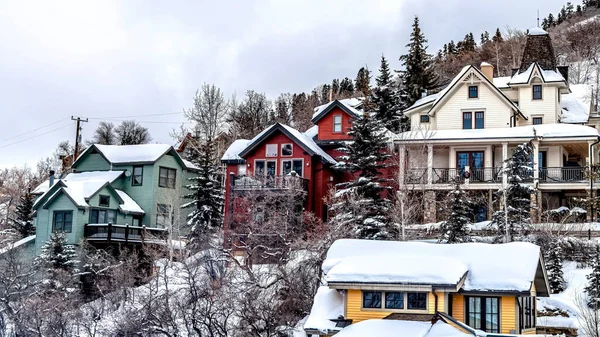 Panorama Coloridas casas familiares ubicadas en un vecindario de colinas con nieve fresca en invierno — Foto de Stock