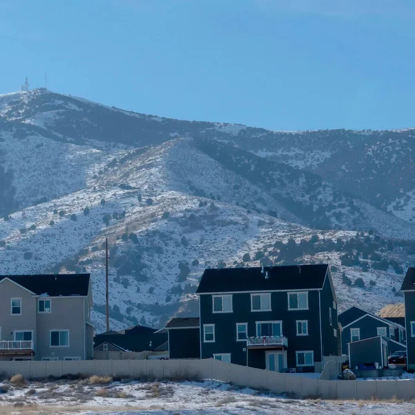 Marco cuadrado Fila de casas contra colinas nevadas y cielo azul en un sombrío día de invierno — Foto de Stock