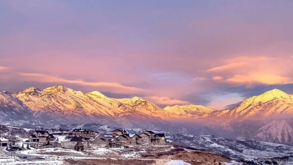 Дома на заснеженном холме на фоне замерзшей горы Васатч с золотым сиянием на закате — стоковое фото