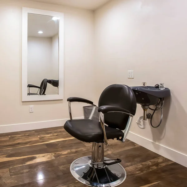 Square frame Hairdresser chair and backwash shampoo bowl inside salon with bench and mirror