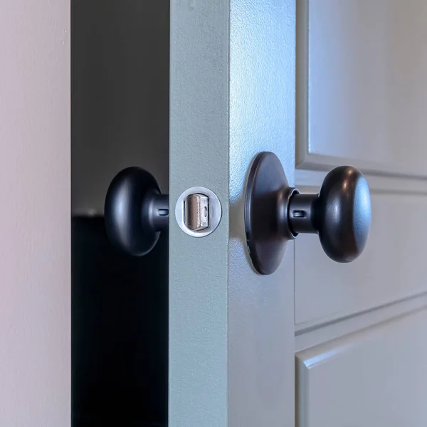 Čtvercový rám Částečně otevřené domácí ložnice závěsné dřevěné šedé dveře s černým klikou — Stock fotografie