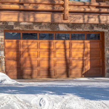 Park City Utah 'ta kışın karlı garaj yolu olan lüks bir ahşap evin ön cephesi.