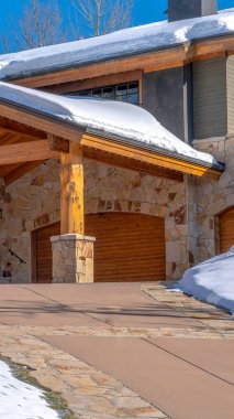 Dikey Ekin Evi Park City Utah 'ta. Karlı çatılı çatıları, taş duvarları ve açık merdivenleri var.