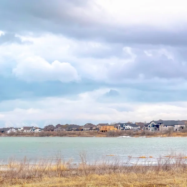 Квадратний урожай Мальовничий озерний пейзаж з резиденціями біля берега під небом з пухнастими хмарами — стокове фото