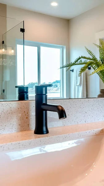 Vertical Sink and faucet against mirror that reflects shower stall and sliding window