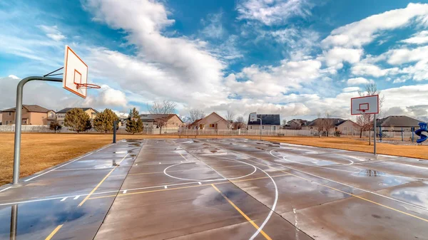 Panorama crop Basketball courts on grassy park with residential neighborhood houses background — Stock Photo, Image