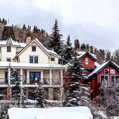 Kışın taze karla kaplı bir tepeye kurulmuş renkli aile evleri.