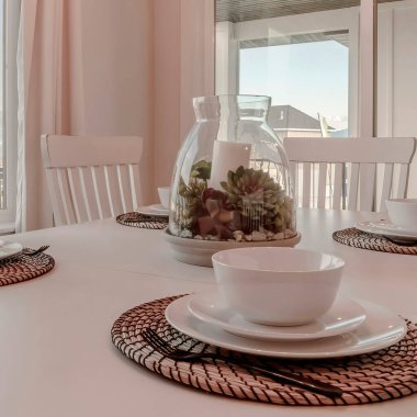 Masa örtüsü ve masa örtüsü ile kare çerçeve yemek masası bir süs etrafına dizilmiş.