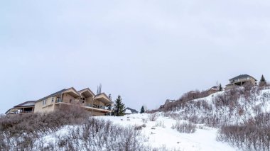 Panorama çerçeveli evler soğuk bir kış gününde taze beyaz karla kaplı bir tepenin üzerine kurulmuştu.