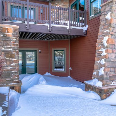 Çift cam kapılar ve karlı giriş üzerinde balkon ile Square Mountain ev cephesi