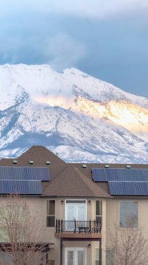 Evin çatısında kışın göl ve karlı dağ zeminli dikey güneş panelleri