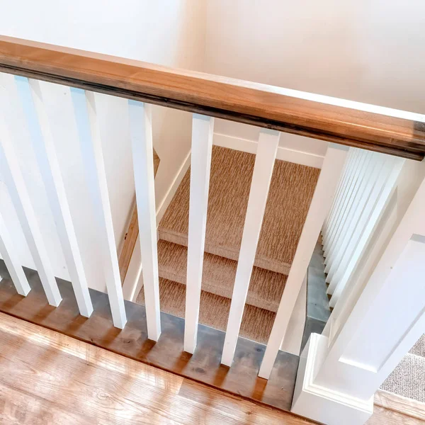 Carré regardant vers le bas sur escalier intérieur en forme de U avec balustre blanc et balustrade brune — Photo