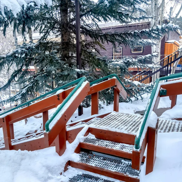 Escaleras cuadradas con pasamanos verdes y bandas de rodadura metálicas de rejilla construidas en la colina con nieve fresca — Foto de Stock