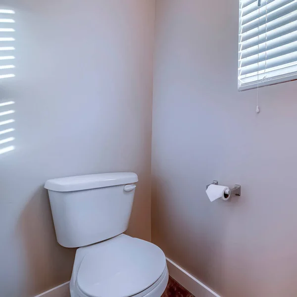 Čtvercový rám WC na rohu koupelny proti šedé stěně s držákem na role tkáně — Stock fotografie