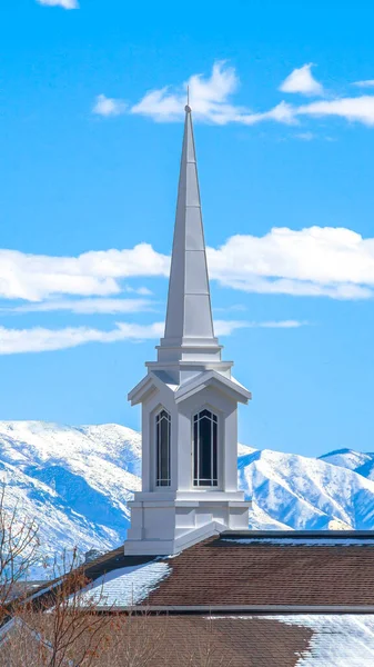 Vertical Rooftop of church with a modern spire design against snowy mountain and lake — Stock Photo, Image