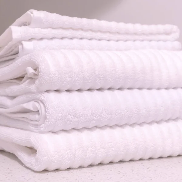 Square Vikta vita handdukar och prydnadsväxt inomhus på badrummet bänkskivan — Stockfoto