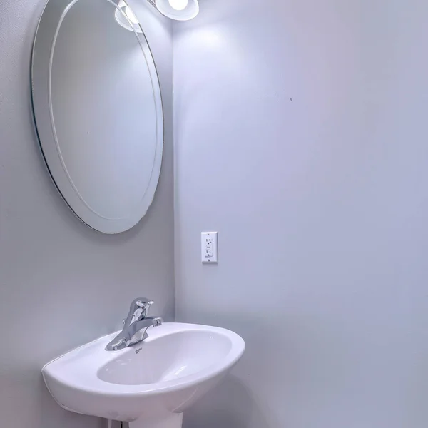 Square Bathroom interior with wall light and oval mirror over stand alone pedestal sink — Stock Photo, Image