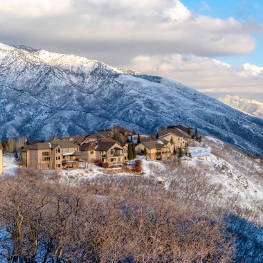 Kışın bozulmamış karlı doğa manzarasını alan Wasatch Dağı evleri.