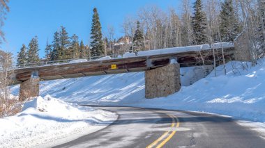 Panorama Paved yolu ve karlı köprü Kışın güneşli karla kaplı tepenin üzerinde