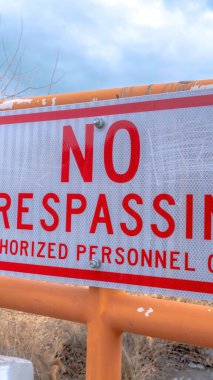 Uzak göl ve bulutlu gökyüzüne karşı eski metal bir çitin üzerinde dikey geçiş yasak işareti