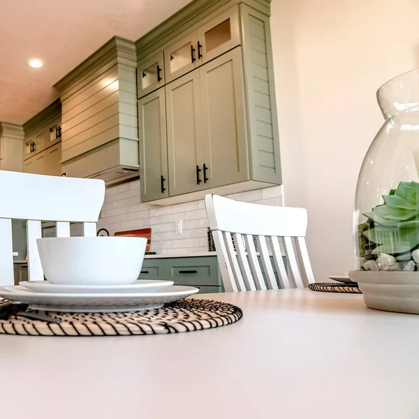 Square frame Tableware and utensils on dining table with view of kitchen in the background